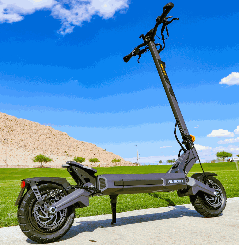 Ausom DT2 Pro electric scooter with 52V 23.4Ah battery, dual 1100W brushless motors, 71 miles range, 42 mph max speed, and 10"x3" tubeless rubber tires on a paved path with grassy background.