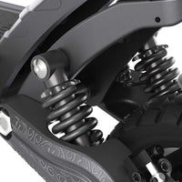 Close-up of Ausom F1 Max Trottinette électrique suspension system with spring shocks and tire details
